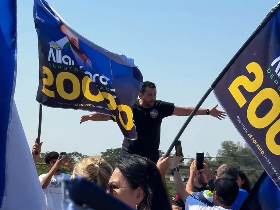 Allan Kardec de braços abertos em ato de campanha, cercado de bandeiras 20020