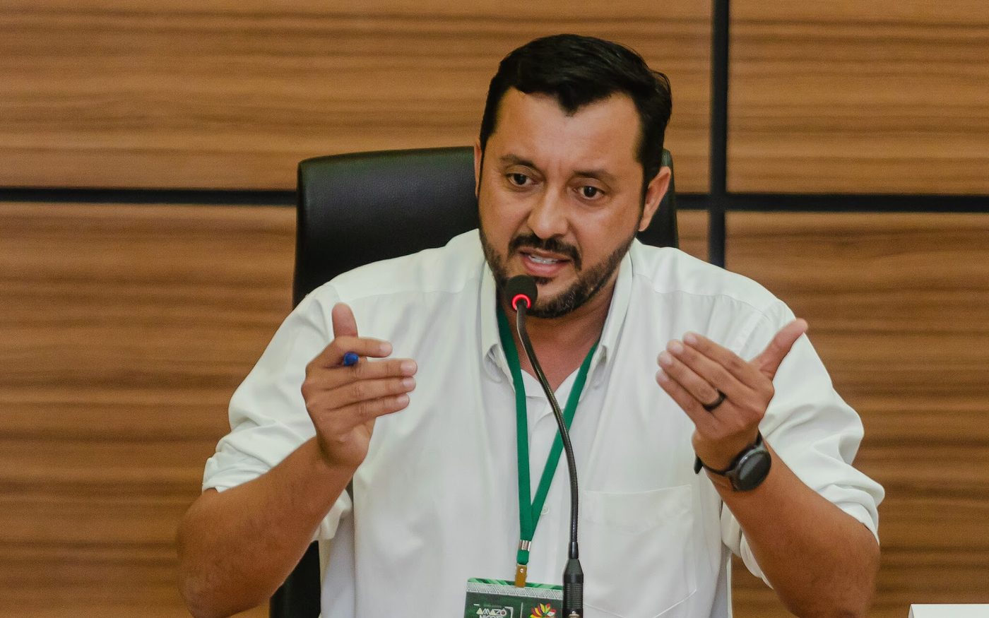 Allan Kardec gesticula ao falar ao microfone durante reunião oficial